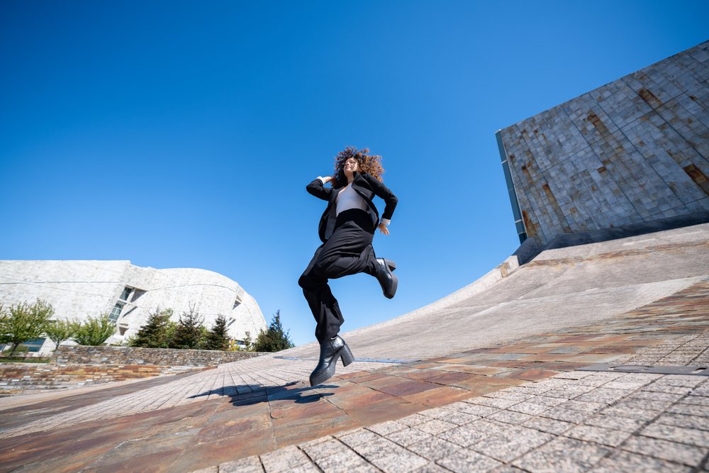 Businesswoman jumping outdoors near modern architecture in Santiago de Compostela, traveling executive, Spain, Santiago de Compostela.