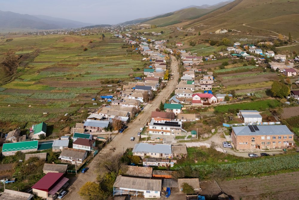 Aerial view of Fieoletovo village showing houses along a main road with surrounding farmland and mountains in Armenia's Aghstev River Valley.