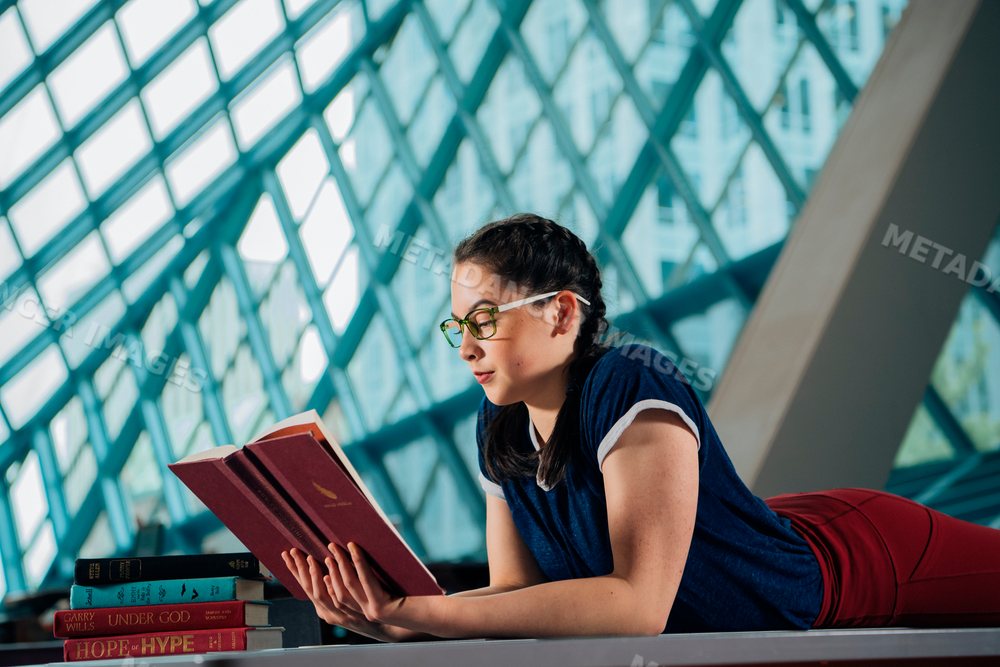 Young woman reading books in a public library in a library