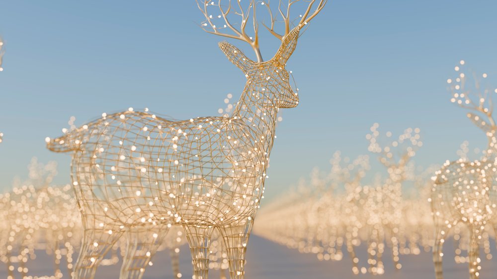 Wireframe reindeer sculptures decorated with glowing lights in an outdoor festive display under clear sky.