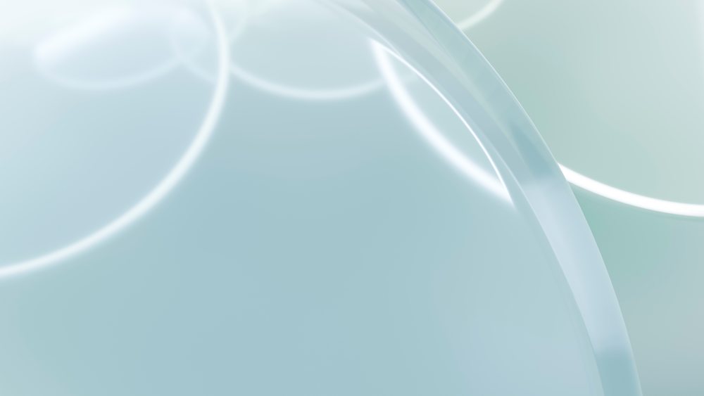 Close-up of a transparent circular laboratory petri dish on a light blue surface used for microbiology research.