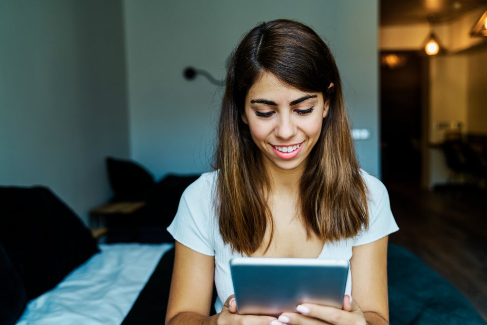 A young woman happily using a tablet indoors