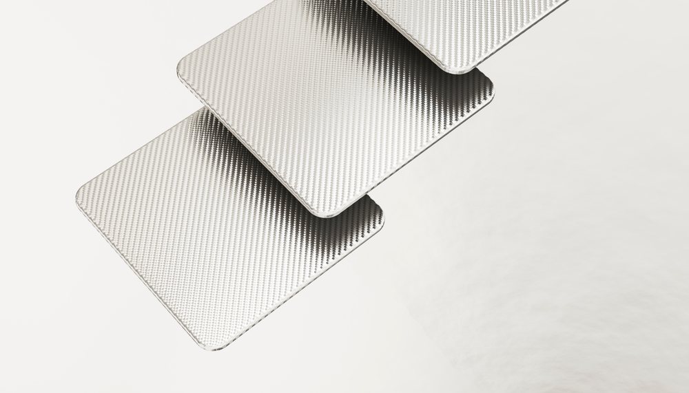 Stacked carbon fiber sheets with visible distinctive weave texture on a white background.