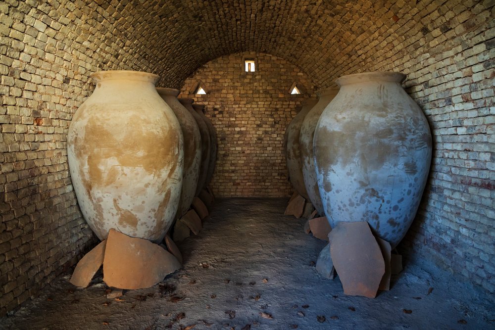 Large rounded qvevri clay wine vessels are arranged inside a brick arched kiln chamber in Georgia awaiting firing.