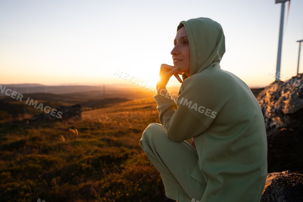 White Woman wearing hoodie sitting outdoors at sunset in Galicia Spain