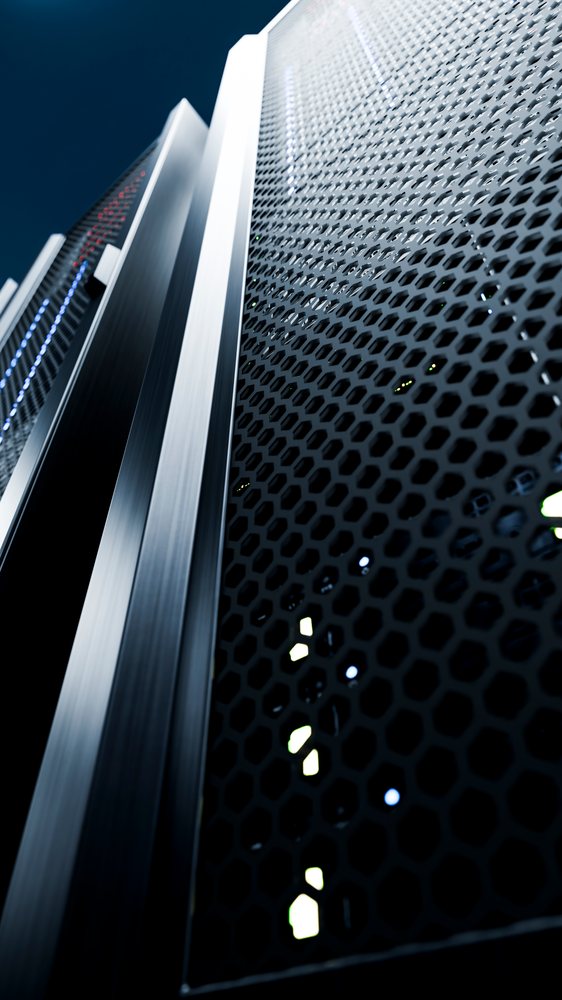 Vertical black metal server racks with ventilated panels and LED indicator lights in a data center environment.