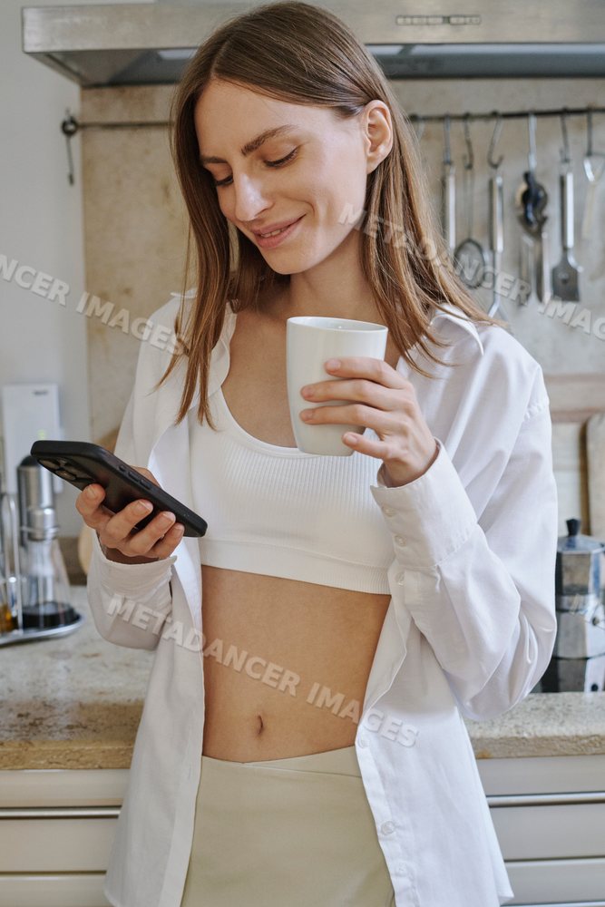 Young white woman drinks coffee and texts on smartphone