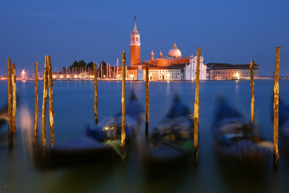 San Giorgio Maggiore church on its island at dusk with moored gondolas across calm water, Venice, Italy.