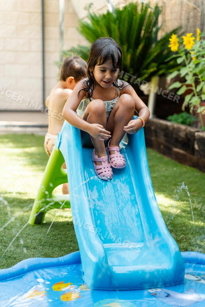 A white girl slides down a water slide into a splash pool