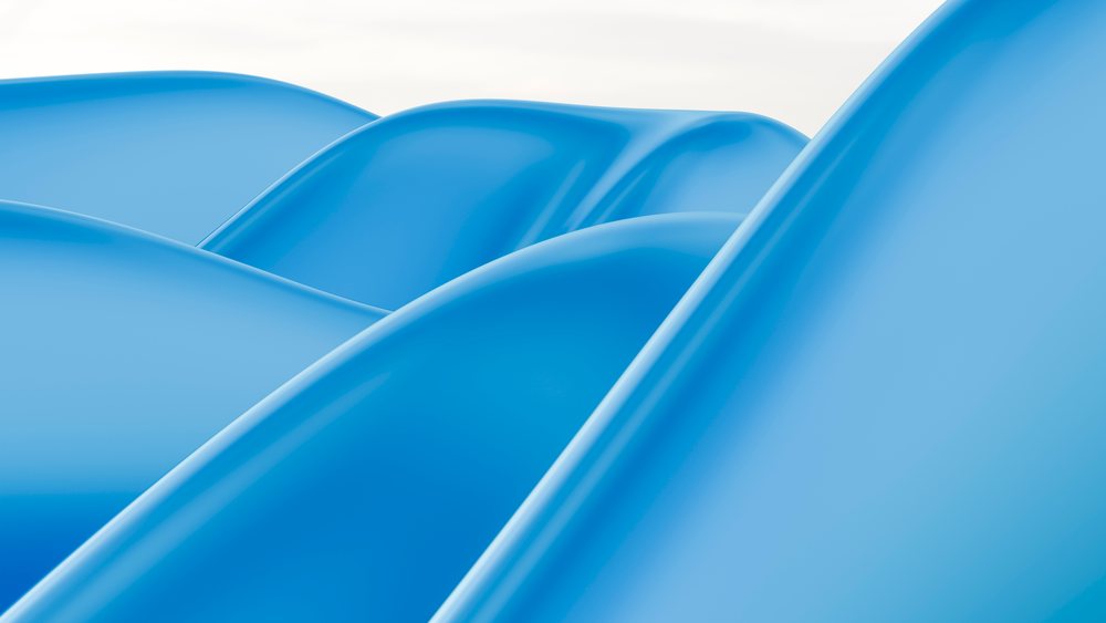 Curved blue plastic playground slides with smooth surfaces in an outdoor playground setting.