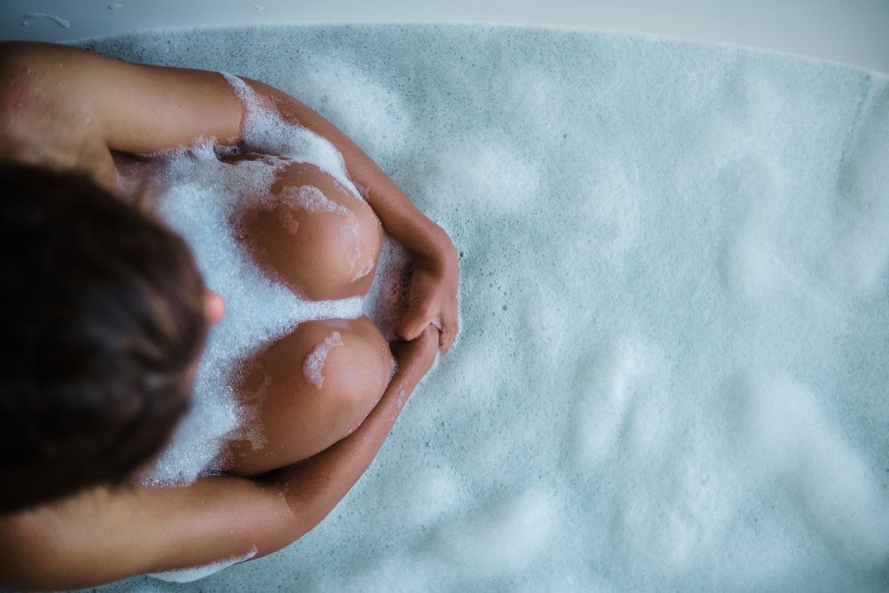 A person relaxing while sitting curled up in a bubble bath in a bathtub in the, Maldives.