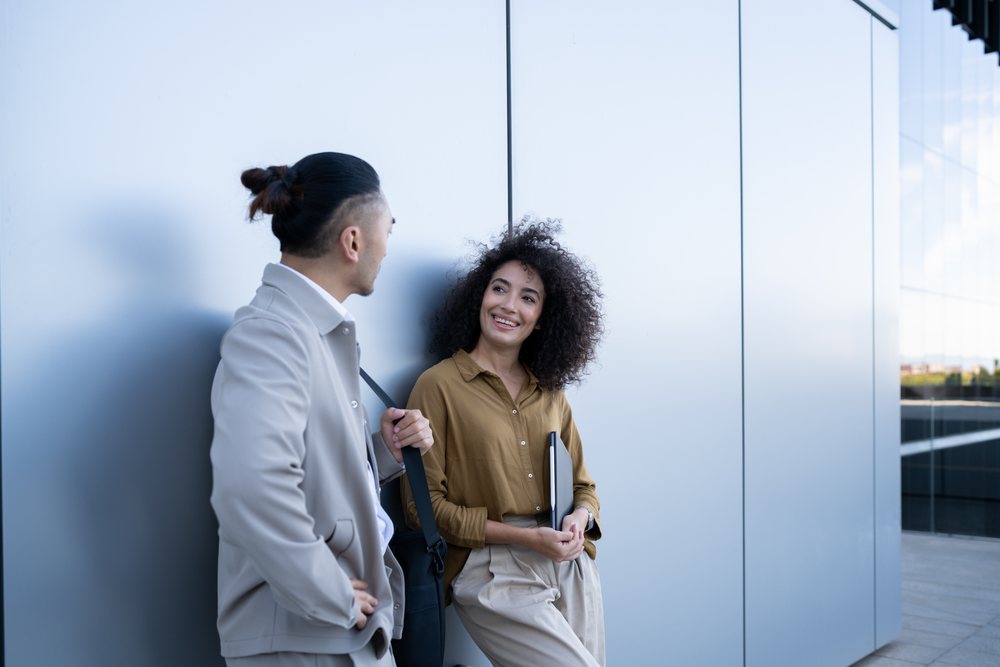 Two people having a friendly conversation outside a modern building in Madrid during the day, Spain.