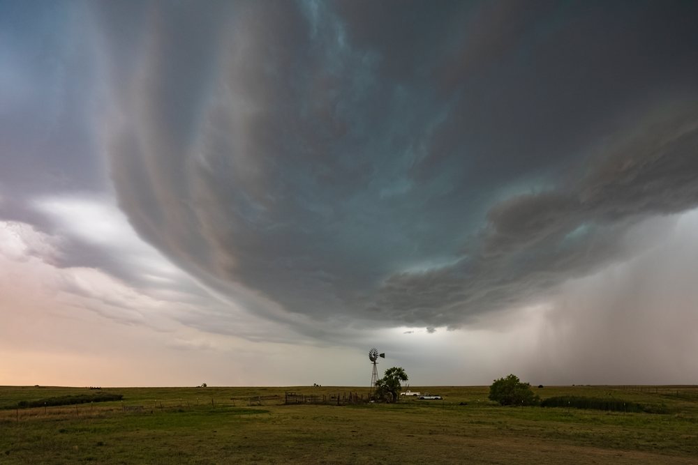 Supercell storm clouds roll over a rural grass field with a windmill and trucks, Storm Chasing, Weather, Environmental issues, Shattuck, Oklahoma, USA.