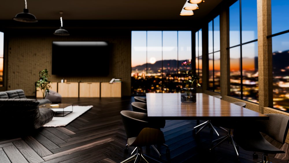 Modern conference room with a large wooden table, chairs, and cityscape visible through floor-to-ceiling windows at sunset.