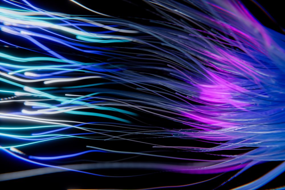 Fiber optic strands rendered in glowing blue and purple light against a black background in an abstract digital art style.