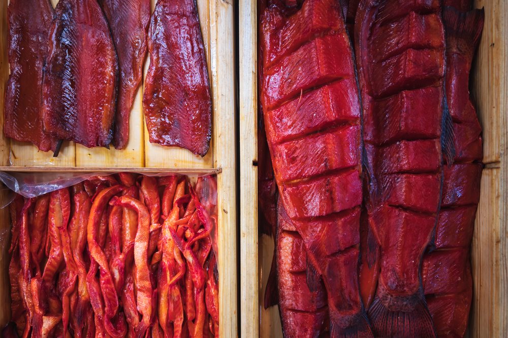 Smoked salmon fillets, whole fish portions, and packed fish strips displayed in wooden compartment boxes, Tsovagyugh, Armenia.