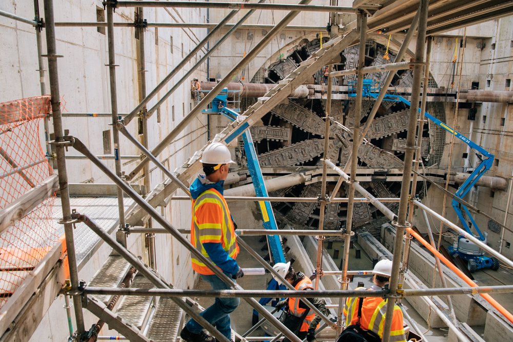Construction workers inspect a large tunnel boring machine inside a concrete shaft at a construction site, Bertha, drilling, USA.