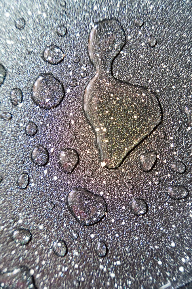 Close-up of water droplets forming an abstract textured pattern on a wet reflective surface, texture, abstract texture, background, wallpaper, Spain.