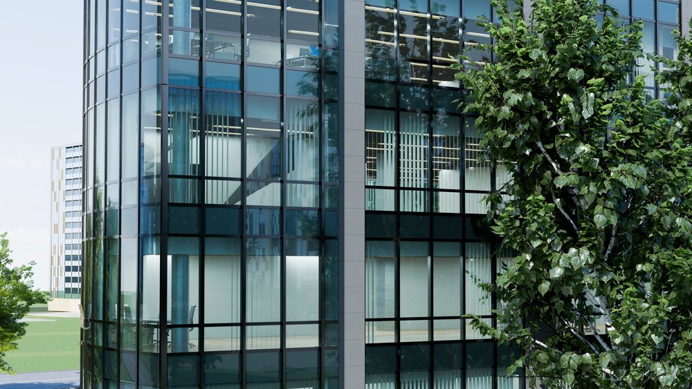Modern office building with reflective glass windows and a green tree nearby in an urban setting during daytime.