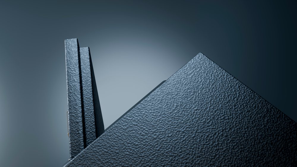 Abstract modern sculpture featuring textured geometric shapes illuminated by blue studio lighting creating shadow effects.