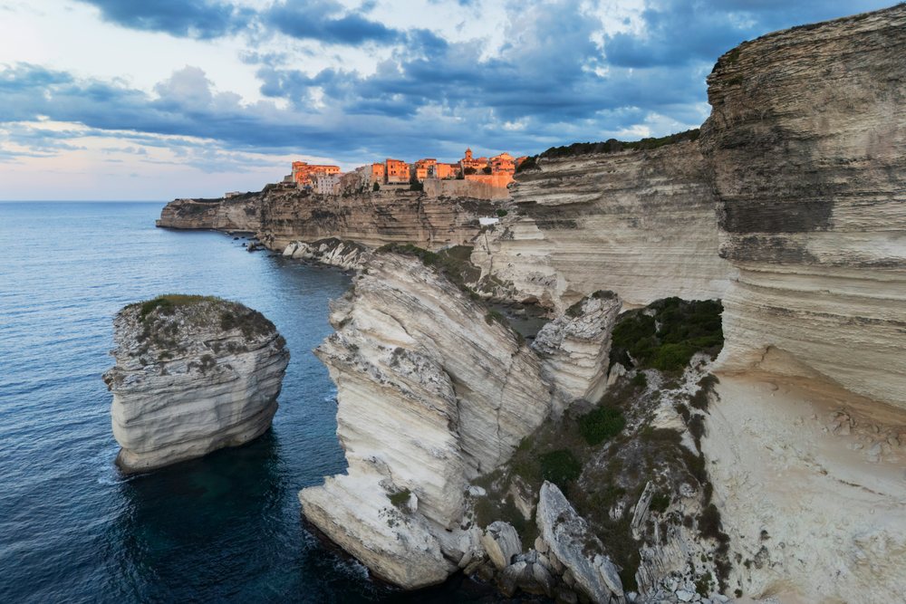 Sunrise illuminates the Citadel of Bonifacio atop rocky cliffs overlooking the Mediterranean Sea, Travel photography, Corsica, France.