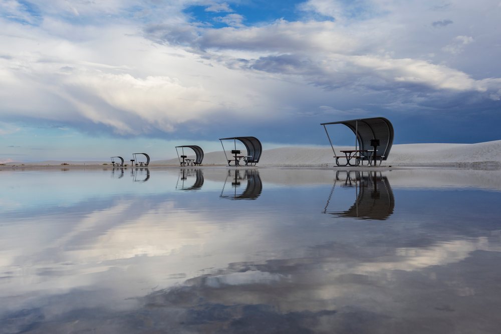 Cabanas with picnic tables reflected clearly in the flooded amphitheatre amid white sand dunes at white Sands National Monument, Landscape, Wildlife, Alamogordo, New Mexico, USA.