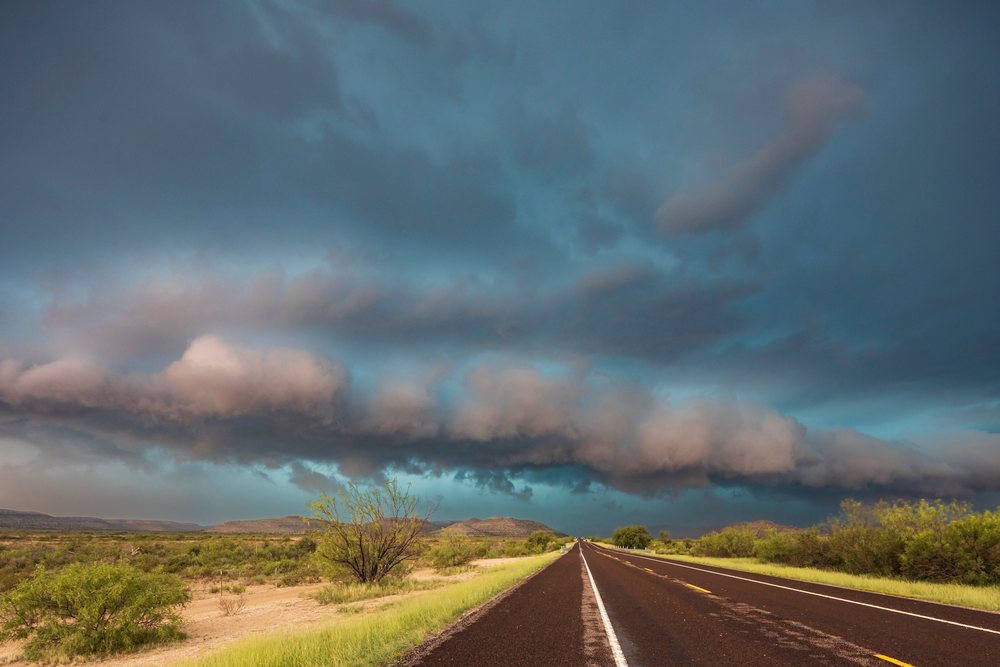 Approaching storm moves over Highway 90 with dramatic dark clouds over desert landscape, Sanderson, Texas, USA.