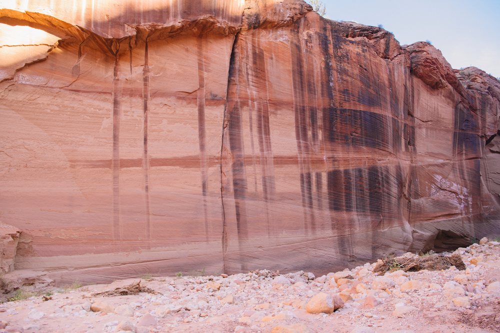 Slot canyon rock wall in Utah USA shows vertical dark streaks, sandstone layers, and natural erosion patterns in an arid outdoor environment, Buckskin Gulch, slot canyon.