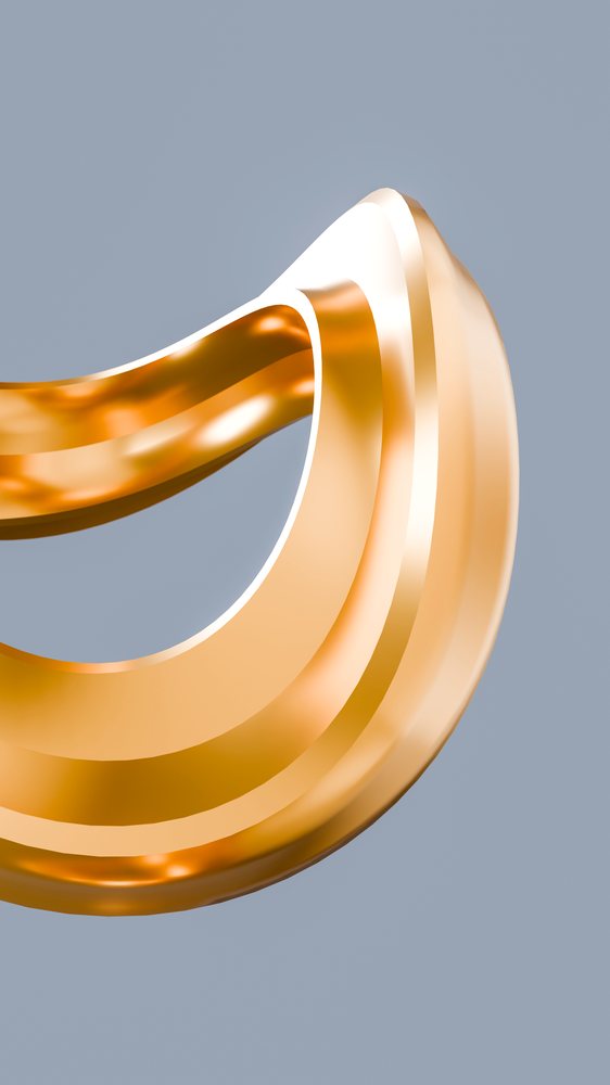 Close-up of a golden curved ring with a shiny polished surface and orange reflections on a gray background.