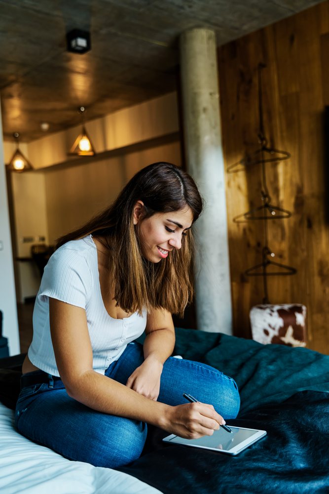 A young woman writing on a tablet in a hotel room in a hotel