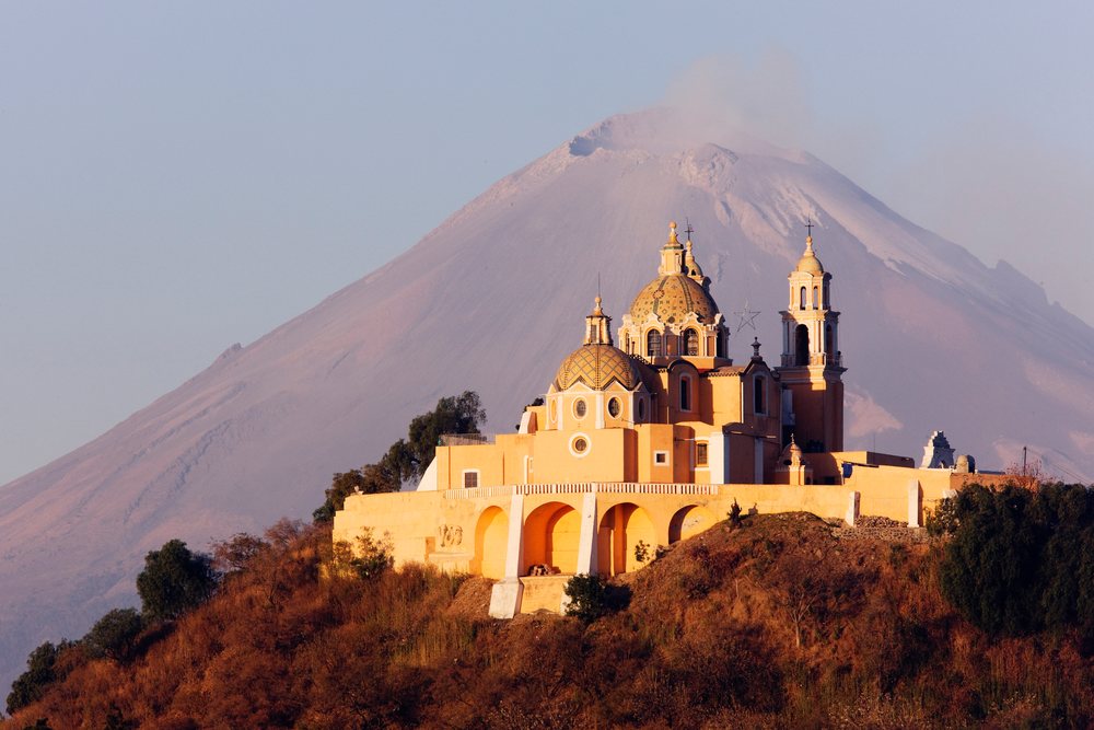 Church of Nuestra Senora de los Remedios on a hilltop with Popocatepetl Volcano visible in the background at sunset, Cholula, Mexico.