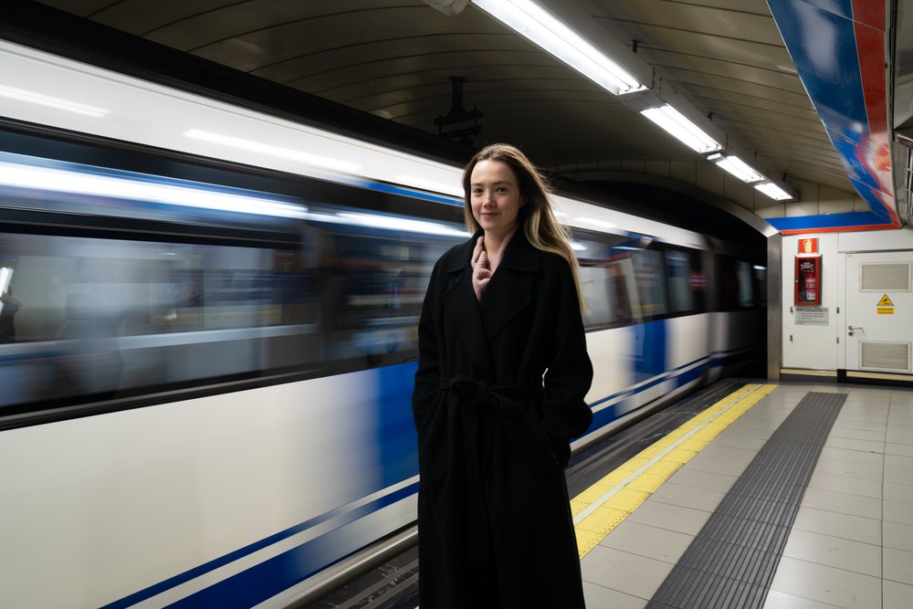 Woman stands on a subway platform as a train passes in an indoor underground metro station, Christmas market, Madrid, Spain.