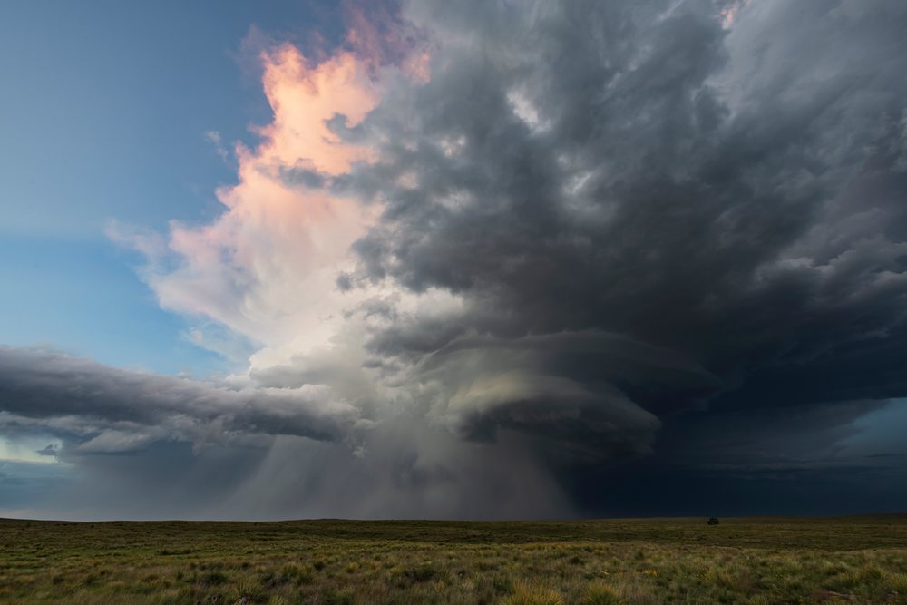Large Supercell thunderstorm with dark clouds and rain over grassland, during sunset, Storm Chasing, Nara Visa, New Mexico, USA.