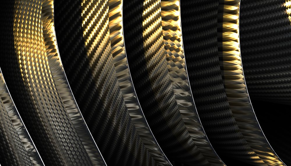 Close-up of textured carbon fiber bands with gold light reflection exhibiting a woven pattern.