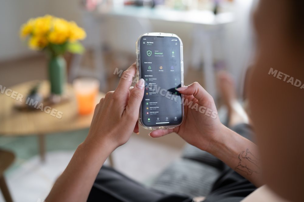 White Person monitors home security system remotely using smartphone