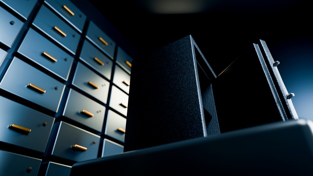 Open metal safe with visible locking pins illuminated next to metal cabinets in a dark setting.