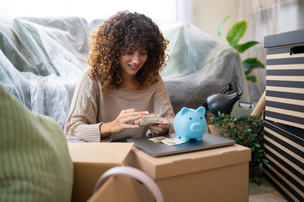 Smiling woman with curly hair counts money indoors, moving, Spain.