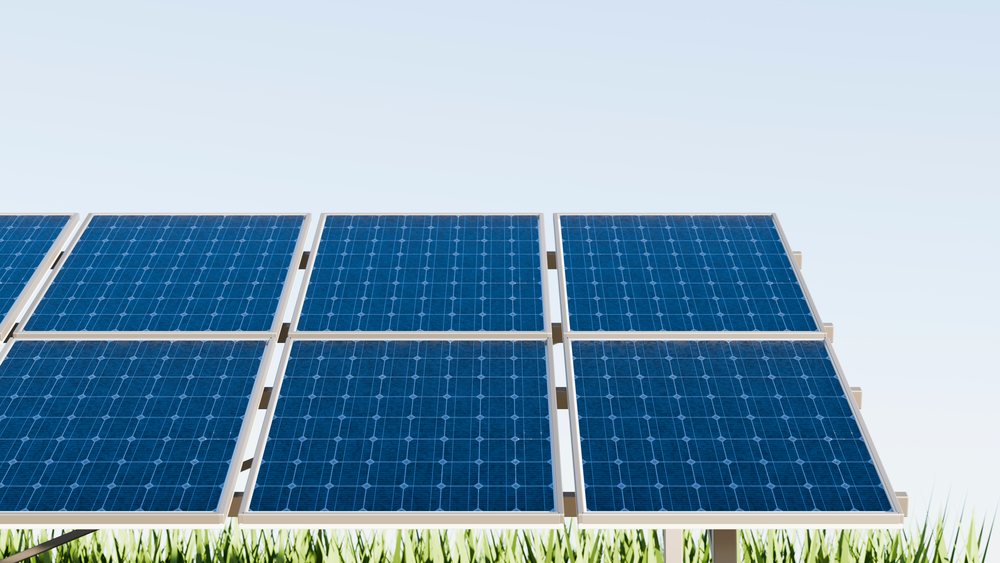 Solar panels installed outdoors generate clean renewable energy under a clear blue sky with green grass beneath.