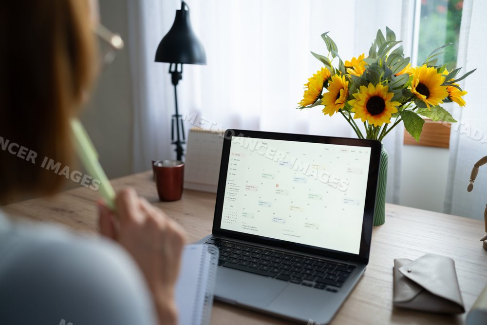 A white person plans their schedule on a laptop calendar
