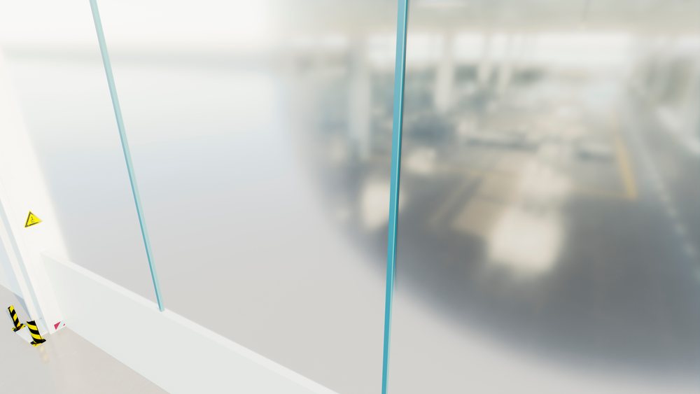 View through a glass wall into the bright, large car manufacturing factory interior with assembly lines and machinery.