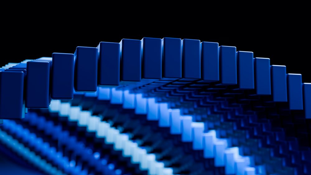 Blue dominoes arranged in a curved arch pattern against a dark background creating an artistic abstract design.