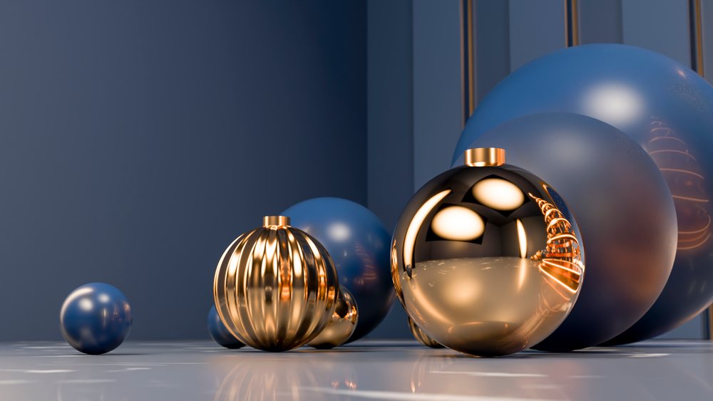 Spherical gold and blue Christmas ornaments with reflective metallic surfaces arranged on a smooth reflective surface in a festive holiday scene.