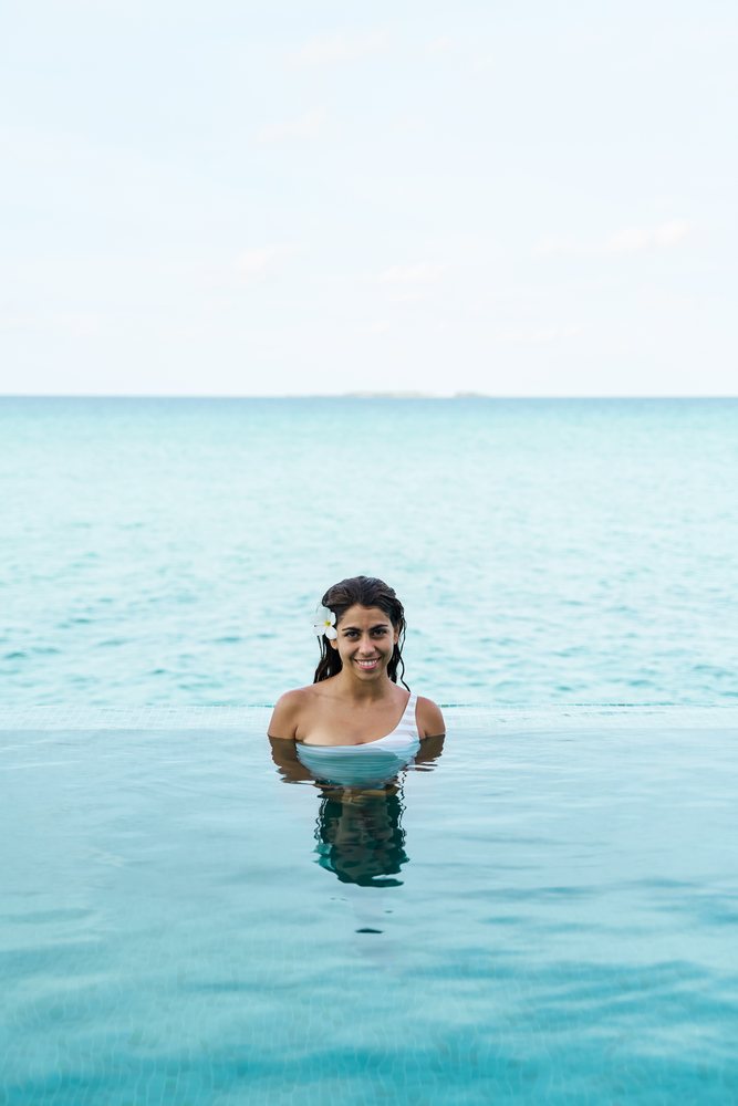 A white woman enjoys an infinity pool overlooking the ocean