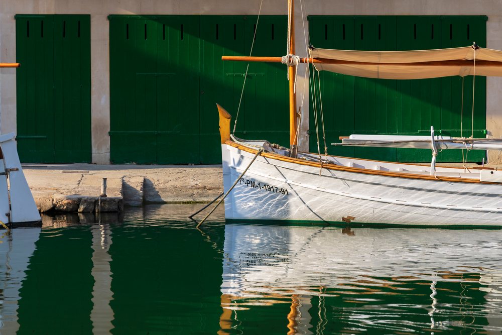 Wooden llaüts boats with white hulls moored in Cala Figuera harbor with green shutters reflected in calm water, Landscape, Lifestyle, Mallorca, Spain.