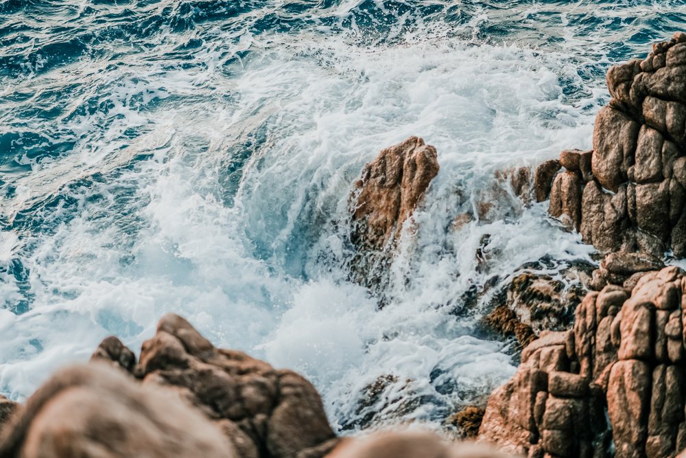 Rough ocean waves crash onto a rocky coastline, creating white foamy sea surf, nature, rough waters, Spain.