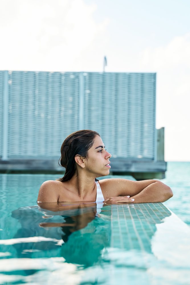 A white woman relaxing at the edge of a swimming pool