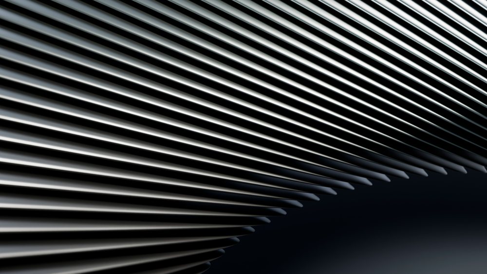 Metal rods arranged in parallel lines form an abstract geometric pattern with shiny silver surfaces on a dark black background.