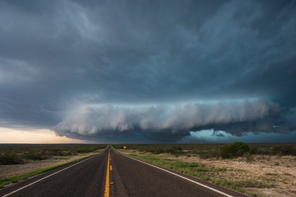Large Mesocyclone storm cloud looms over an empty asphalt road through dry plains, Dryden, Texas, USA.
