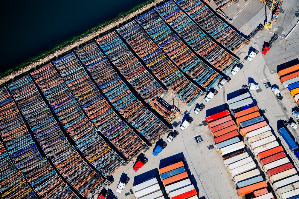 Aerial view of container trucks parked and shipping containers stacked at a major port terminal in Long Beach, California, USA.