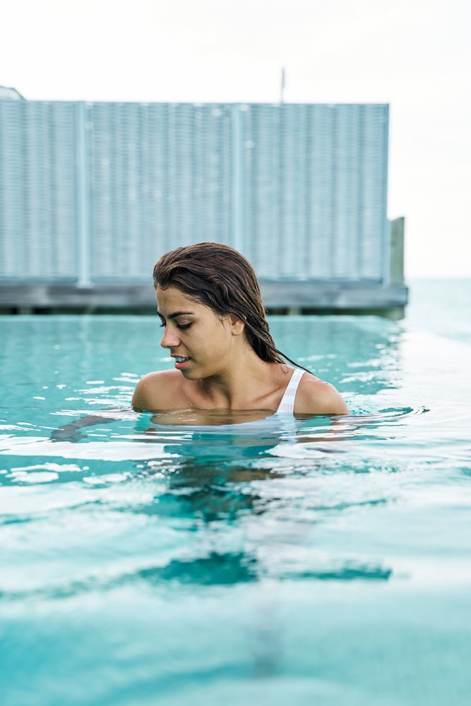 A white woman enjoys swimming and relaxing in a pool